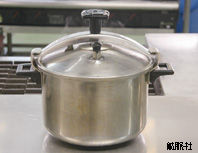 金属製の蓋がしっかりと閉まり上部に黒い取っ手と圧力調整弁のようなパーツが付いた、重厚な造りをした圧力鍋の写真