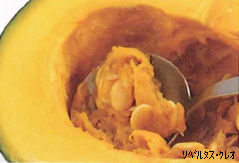 半分に切ったかぼちゃの種とワタをスプーンですくって掻き出している様子の写真