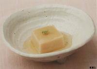淡いだしに浸り上に練りわさびが添えられた薄茶色のごま豆腐の写真