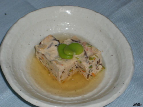 澄んだだしに浸され上にそら豆が添えられた角切りの友禅豆腐の写真