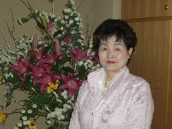 淡いピンク色のレースが施されたジャケットを着用した黒田 留美子さんの写真