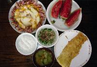 お皿に盛りつけられただし巻きたまご、かぼちゃのチーズのせ、おくらなっとうやかぼちゃとなすのみそ汁、カットされたスイカが並ぶ写真