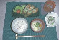 お皿に盛りつけられた断面の彩りが綺麗な肉巻きフライのベジカツ、枝豆と切り干し大根のサラダ、十八こく米、具沢山のだんご汁、麦茶が並ぶ写真