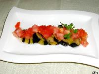 揚げた茄子の上に角切りトマトと緑の葉が彩りよく添えられたトマトとなすのサラダの写真