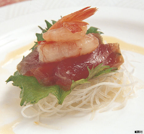 大根のつまを土台に青じそとマグロの赤身が重ねられ上に甘エビがのった刺身の写真