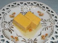 薄いあんが絡む淡い黄色の四角いコーン風味豆腐のわさびあんの写真