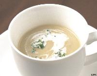 渦状のクリームと緑の薬味が浮かぶ上品な淡いクリーム色のきのこのポタージュの写真