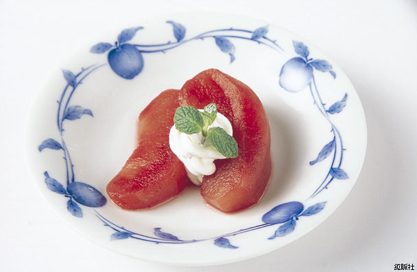 中央に白いクリームとミントが添えられ、赤く煮含めたりんごのコンポートの写真