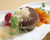 大根おろしが添えられにんじんとトマトが彩りの、こんがり焼かれた和風ハンバーグの写真