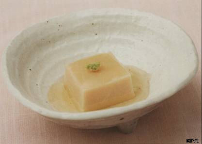 淡いだしに浸り上に練りわさびが添えられた薄茶色のごま豆腐の写真