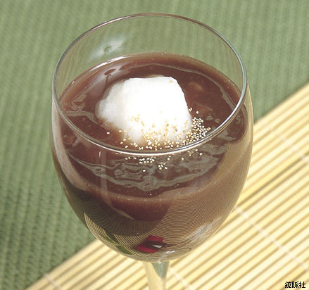 透明なワイングラスの中に、ぜんざいが満たされ、中央に真っ白なご飯だんごが浮かびごまが散る、白玉ぜんざいの写真