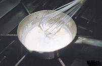 材料を鍋にいれ、泡立て器で混ぜている写真