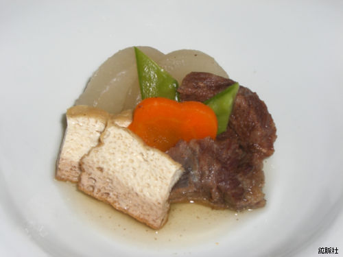 淡い煮汁に浸され人参や絹さやが添えられ彩りよく盛られた牛スジと厚揚げの炊き合わせの写真