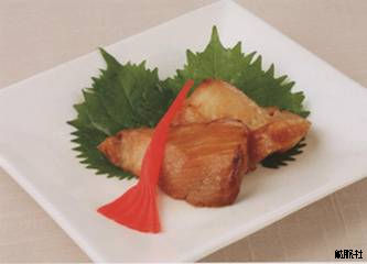 大葉の上に並び赤いショウガの飾りが添えられ、よく焼かれたカラスガレイの照り焼きの写真