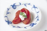 中央に白いクリームとミントが添えられ、赤く煮含めたりんごのコンポートの写真