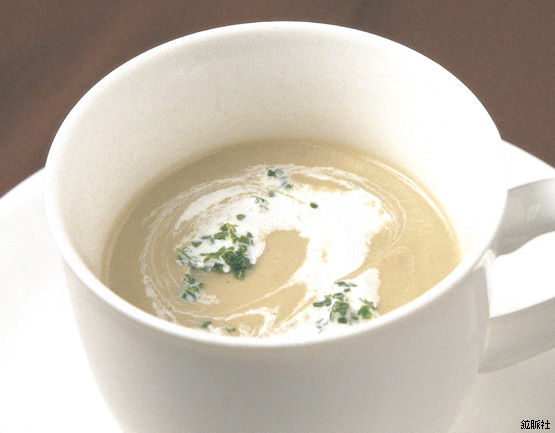 渦状のクリームと緑の薬味が浮かぶ上品な淡いクリーム色のきのこのポタージュの写真