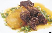 刻んだ青ねぎが散らされ飴色に深く煮込まれた大根と柔らかそうな牛すじの煮込みの写真