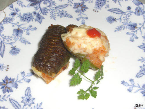 ケチャップとチーズをのせたピラフが詰められた照りのあるピーマンのライス詰めの写真