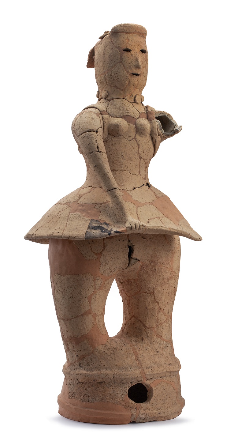 素焼きの質感を持った人型の埴輪であり、豊かな胸の膨らみやスカートのような形状の裾、微笑んでいるような柔らかな表情が特徴的な踊る女性埴輪の写真